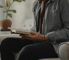 Man sitting on couch reading a Bible