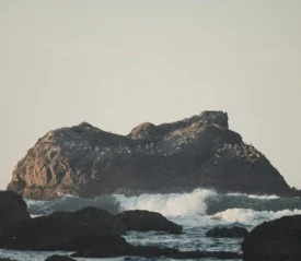 big rock sticking out of rough ocean