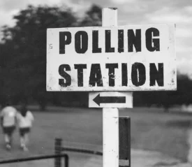 Post sign that reads "POLLING STATION" and an arrow pointing left