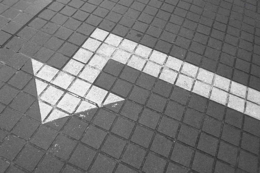 Painted arrow on sidewalk pointing left