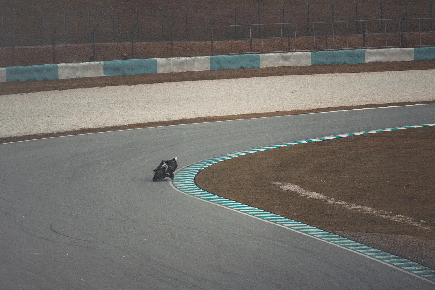 Sport bike taking a low, fast corner on a track marked with teal and white edge lines
