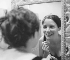 Smiling woman looking at herself in the mirror