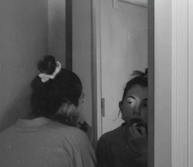 Woman leaning into a mirror putting lipstick on