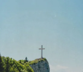 Stone cross on the edge of a rock cliff with clear skies in the background