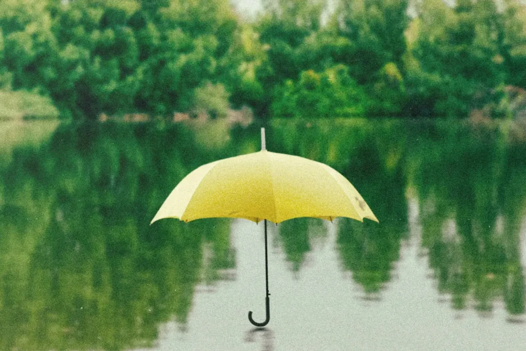 Single yellow umbrella sitting open on a body of water
