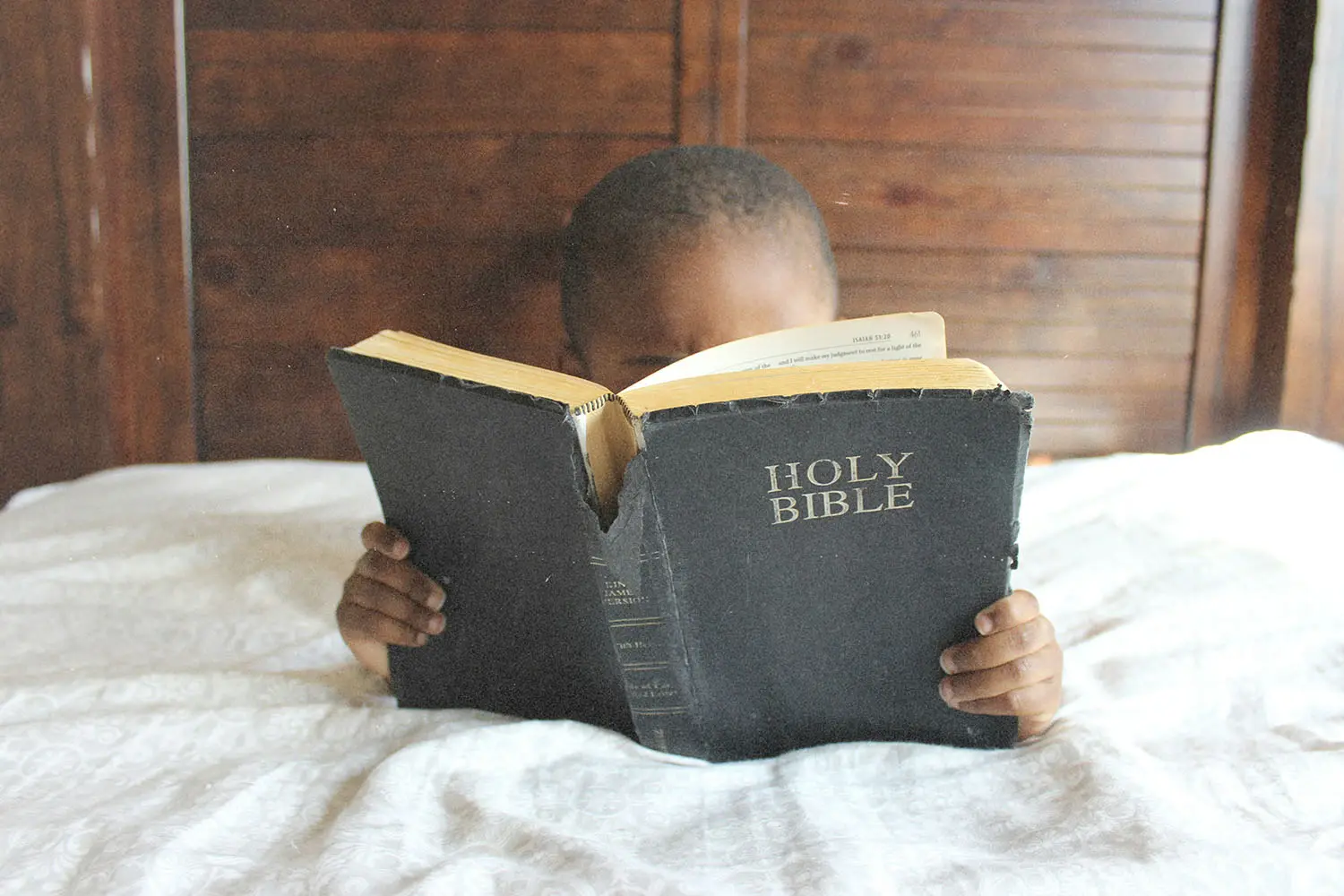 child reading the bible in bed