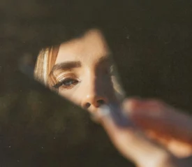 Half of girl's reflection on a chipped piece of mirror