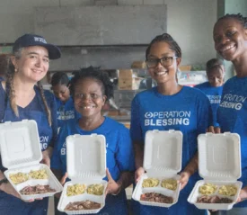 Operation Blessing team holding meal boxes with rice and meat, supporting local communities with food assistance.