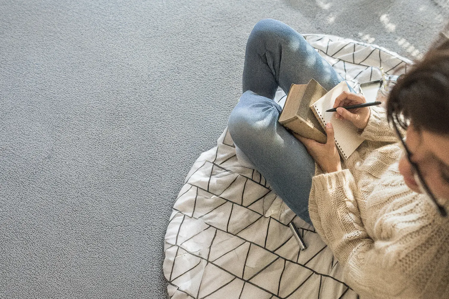 Woman writing in a notebook at a cozy desk, practicing gratitude journaling in a peaceful, softly lit room.