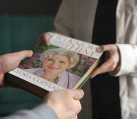 Hands exchanging a book titled To Know God by Gloria Copeland