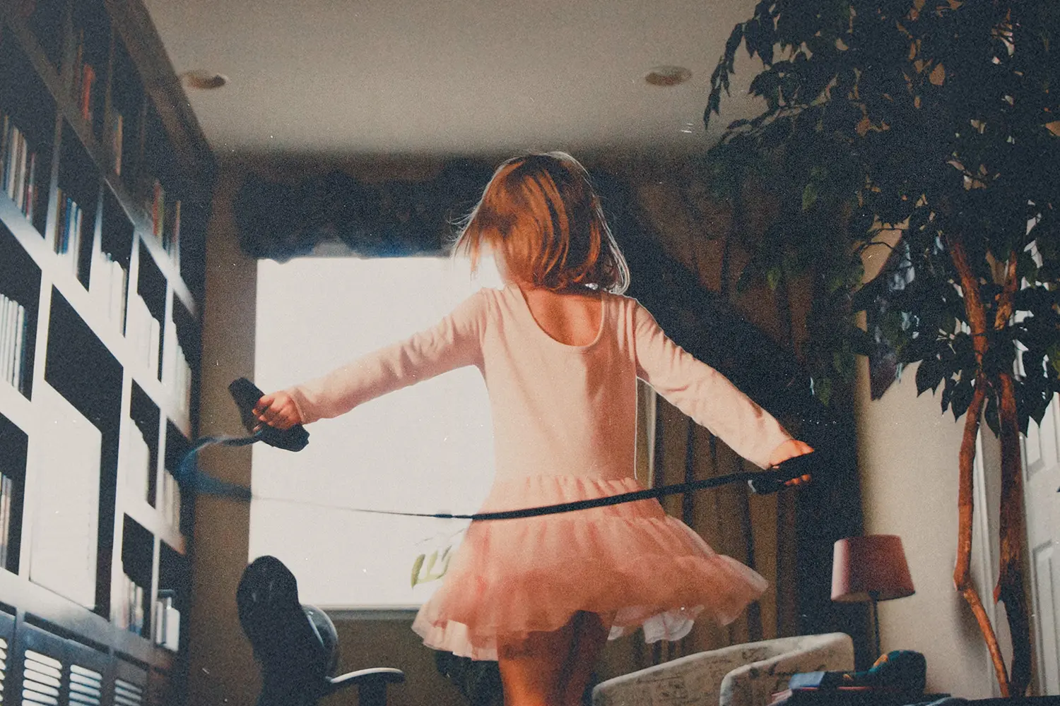 Girl playing in the living room with a jump rope.