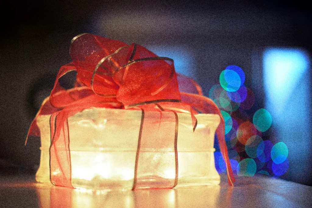 Glowing gift box wrapped with a red ribbon, symbolizing light, hope, and the message that Jesus transforms lives.