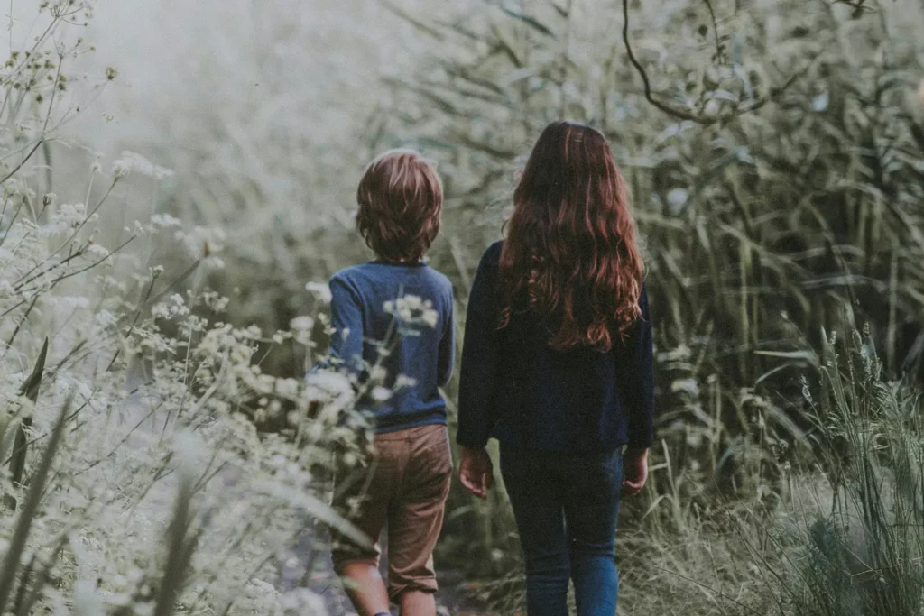 Two children walking along a path through tall greenery, symbolizing guiding Children of God with spiritual authority in a scroll‑driven world today.