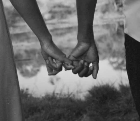 Couple holding hands by water, symbolizing a successful marriage strengthened by the power of prayer and unity in their shared testimony.
