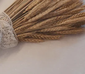 A bundle of dried wheat wrapped in lace resting on a flat surface.