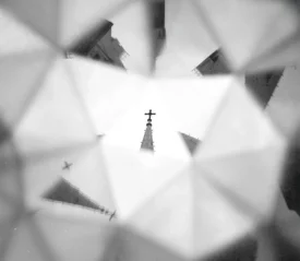A church steeple topped with a cross is reflected and multiplied through a kaleidoscope‑like pattern of geometric shapes