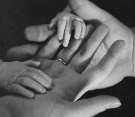Close‑up of adult hands gently holding a baby’s hands