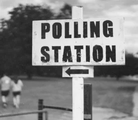 black and white photo of polling station sign with arrow pointing left