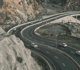 curved road with cars driving. Bolders on one side and a drop off on the other