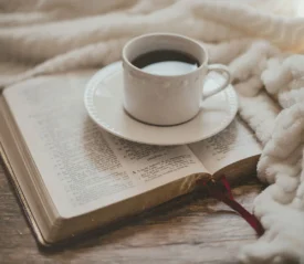 Bible open with coffee mug on top