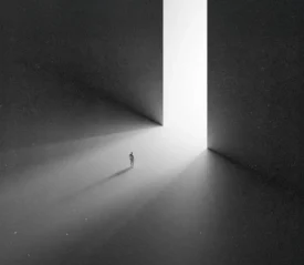 A small figure stands alone in a vast dark space, walking toward a towering doorway filled with bright white light