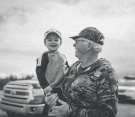older man holding a smiling little boy