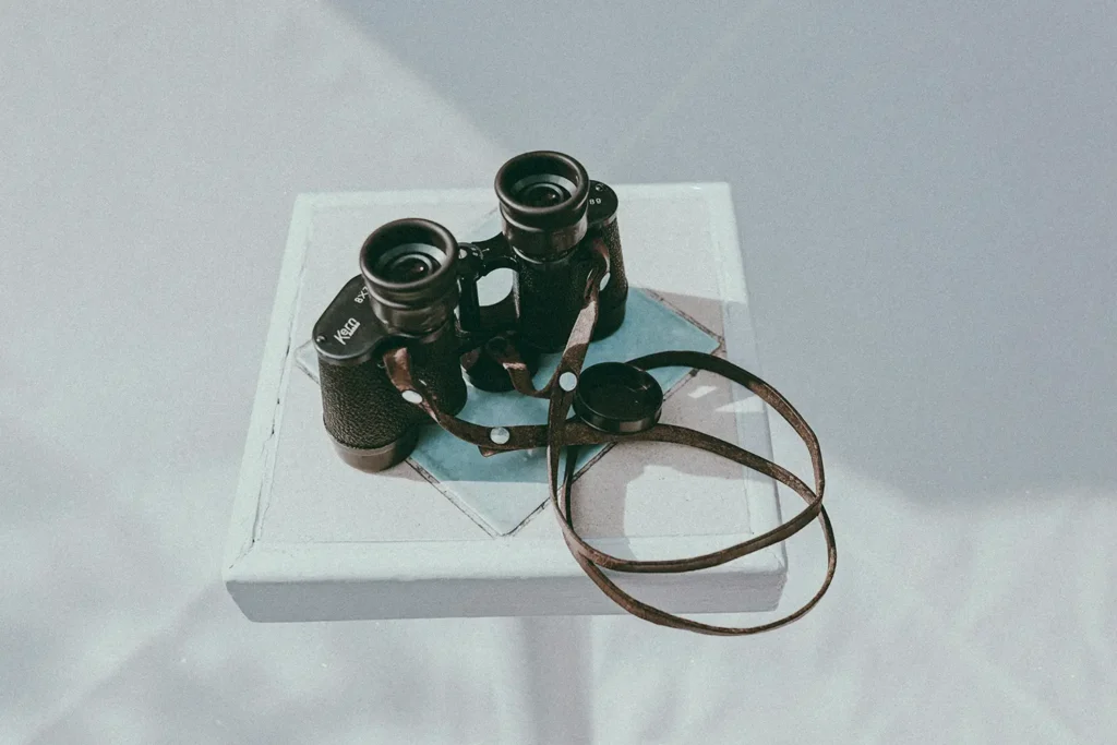 Binoculars and a book on a white table.
