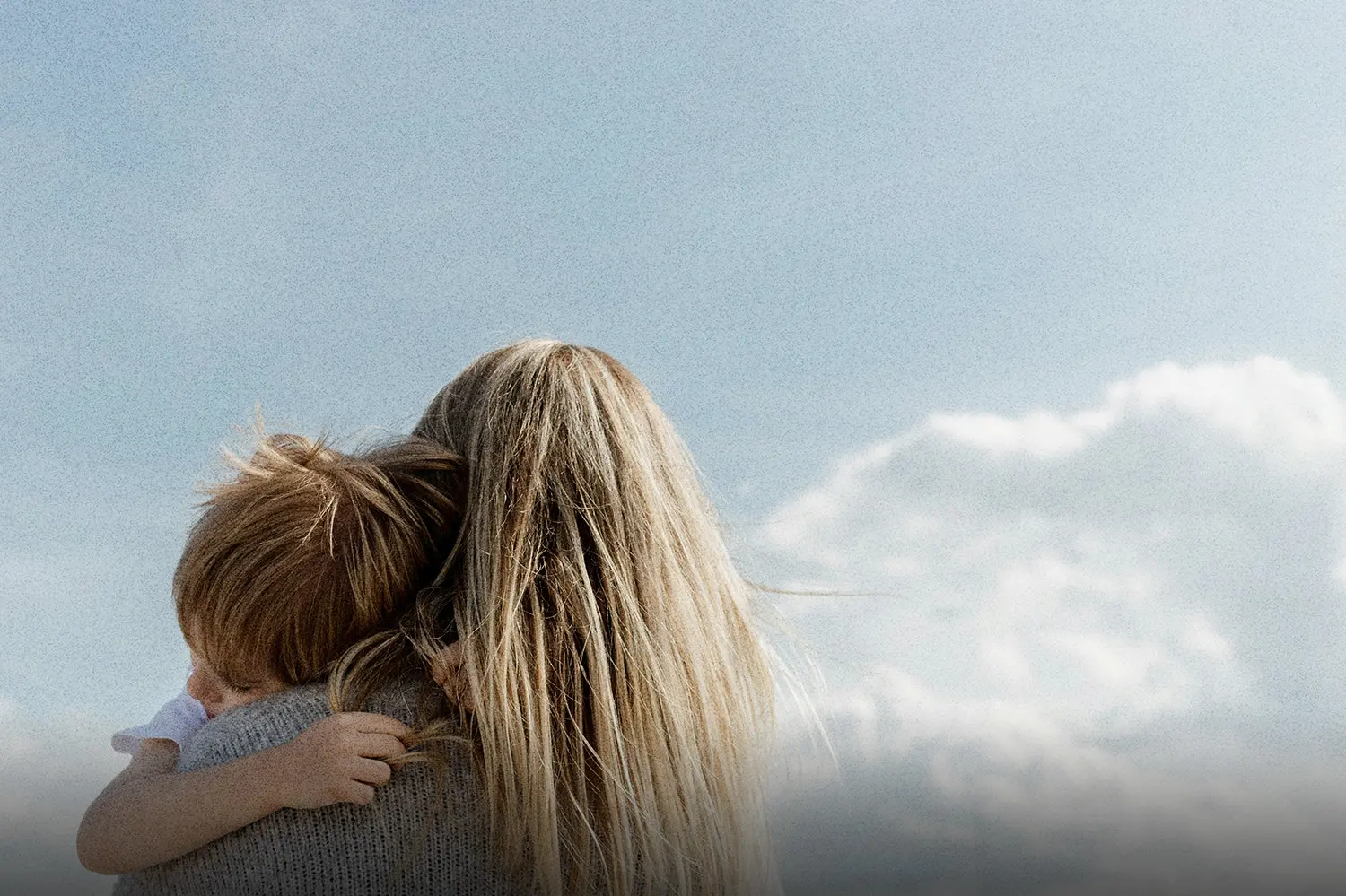 Adult embracing a child outdoors under an open sky, illustrating spiritual motherhood through nurturing presence, guidance, and generational connection.