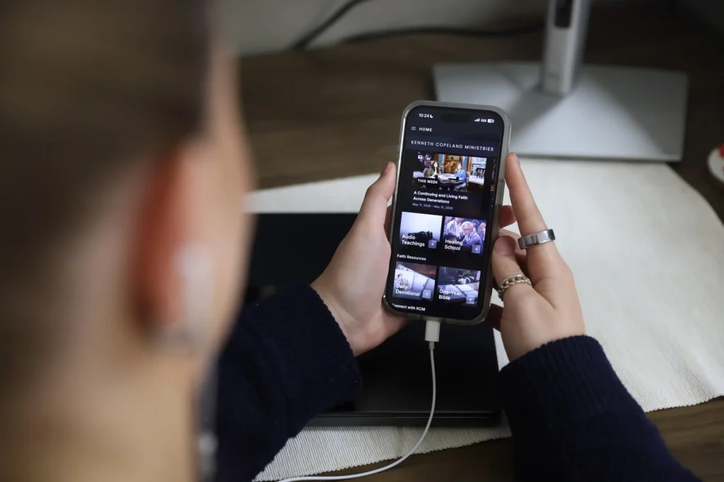Looking over a young lady's shoulder at a mobile app being used.
