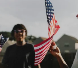 People waving American flags at an outdoor celebration.