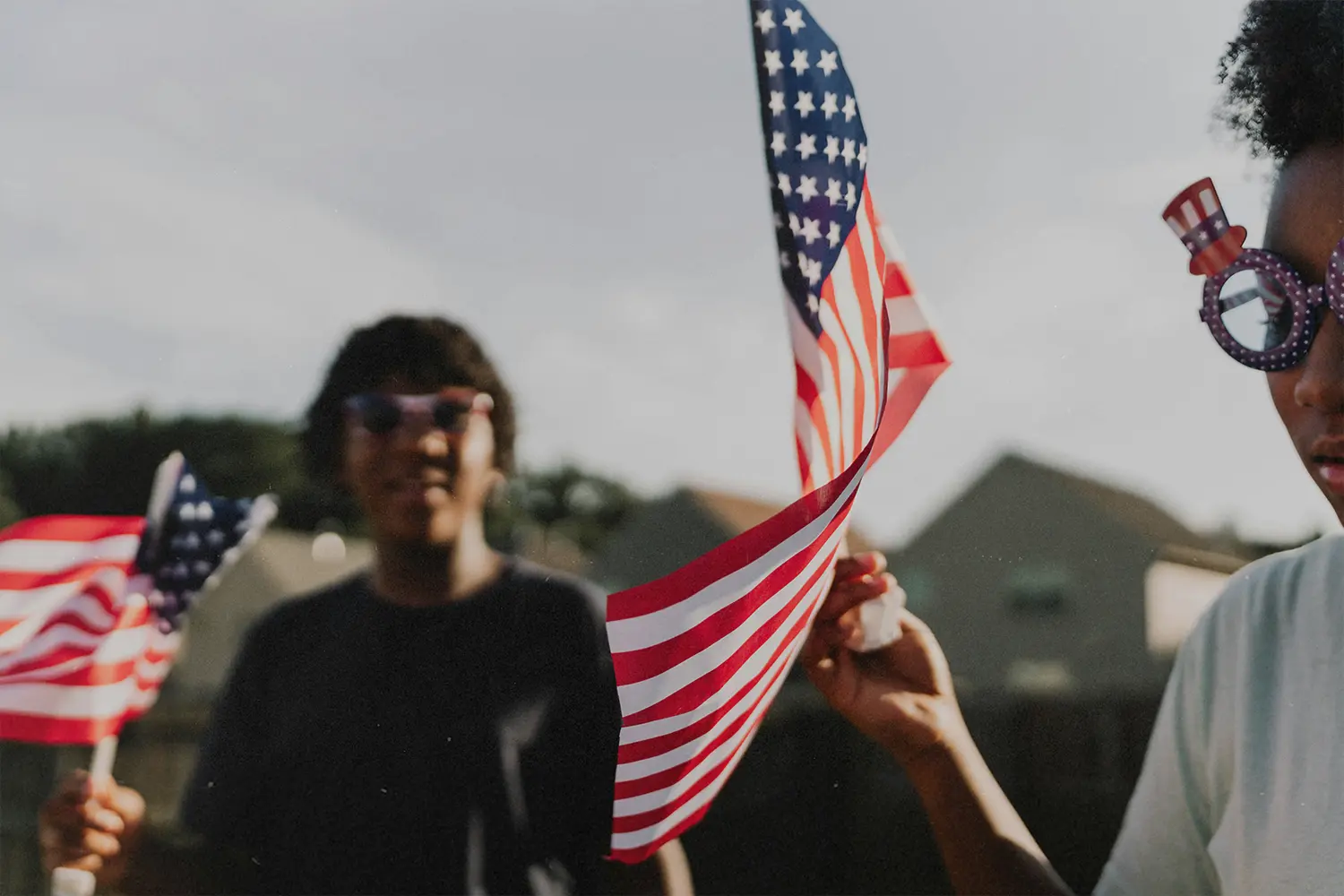 People waving American flags at an outdoor celebration.