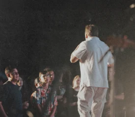 Man standing on stage facing a crowd.
