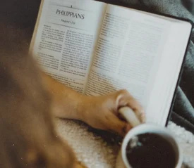 Someone holding a Bible and coffee cup.