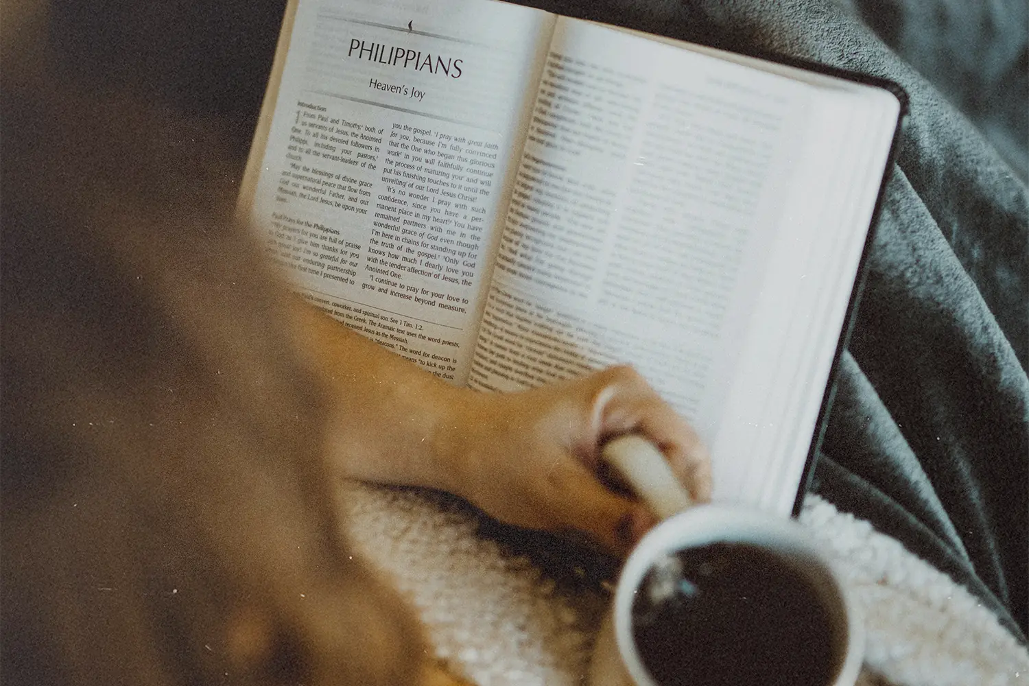 Someone holding a Bible and coffee cup.