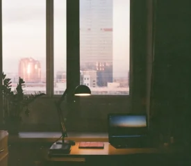 A work desk with a lamp in front of a window.