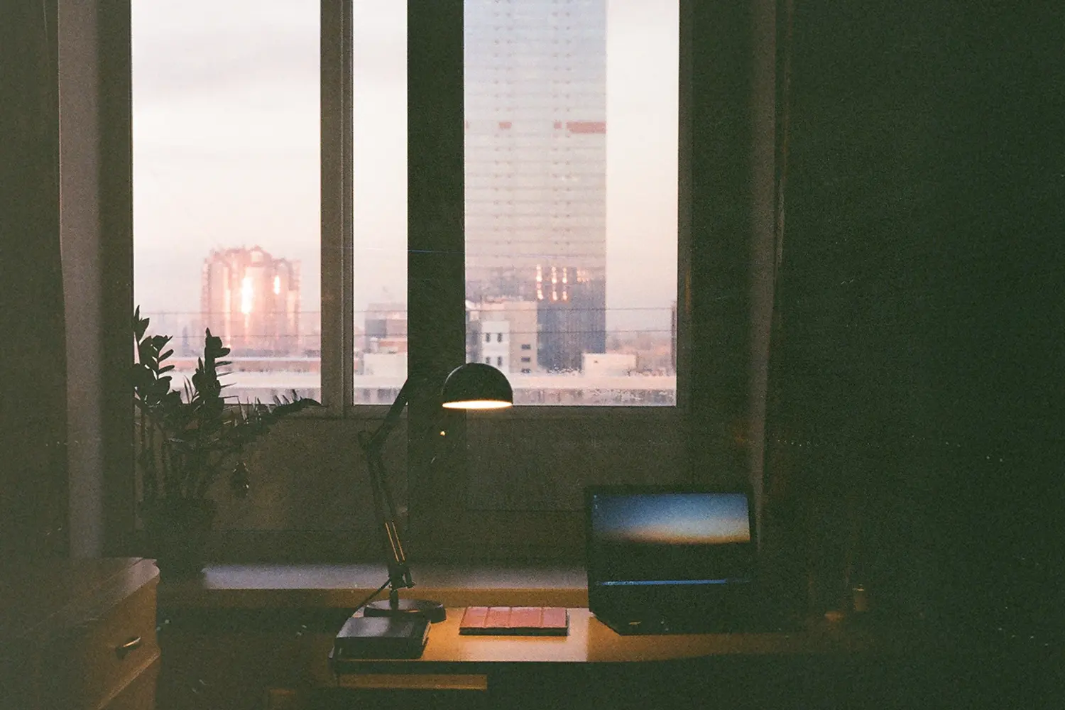 A work desk with a lamp in front of a window.