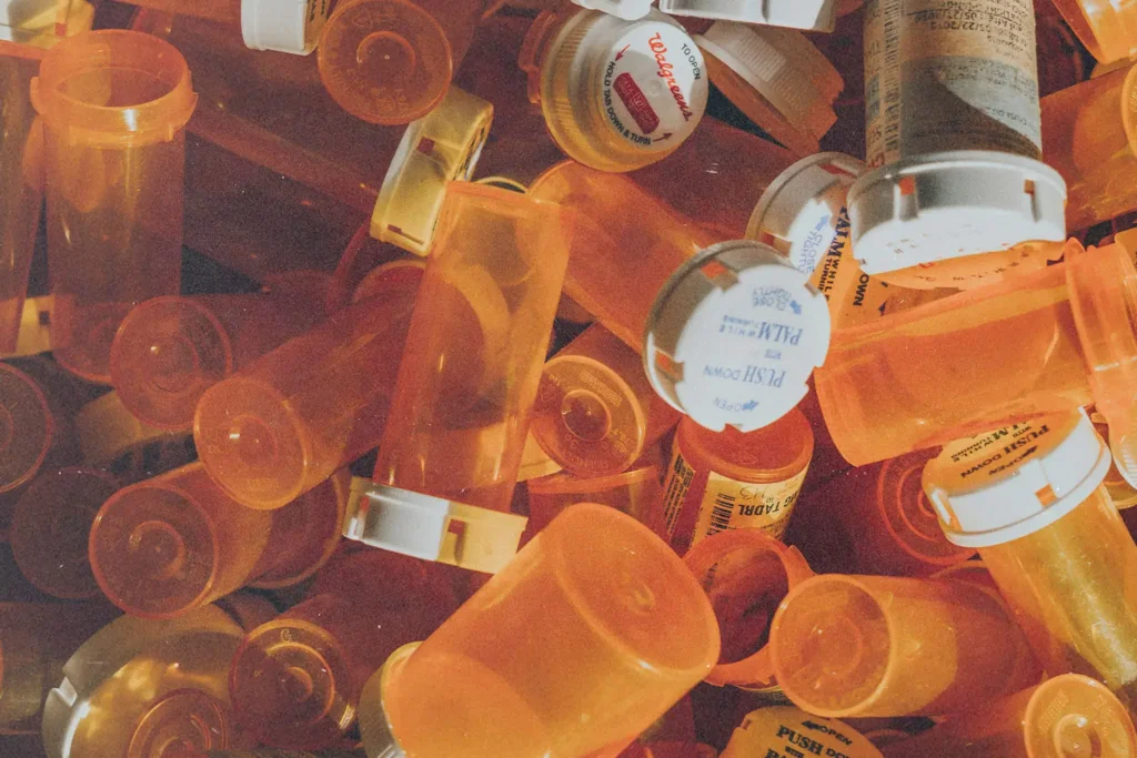 A scattered pile of empty orange prescription bottles with white caps, filling the entire frame