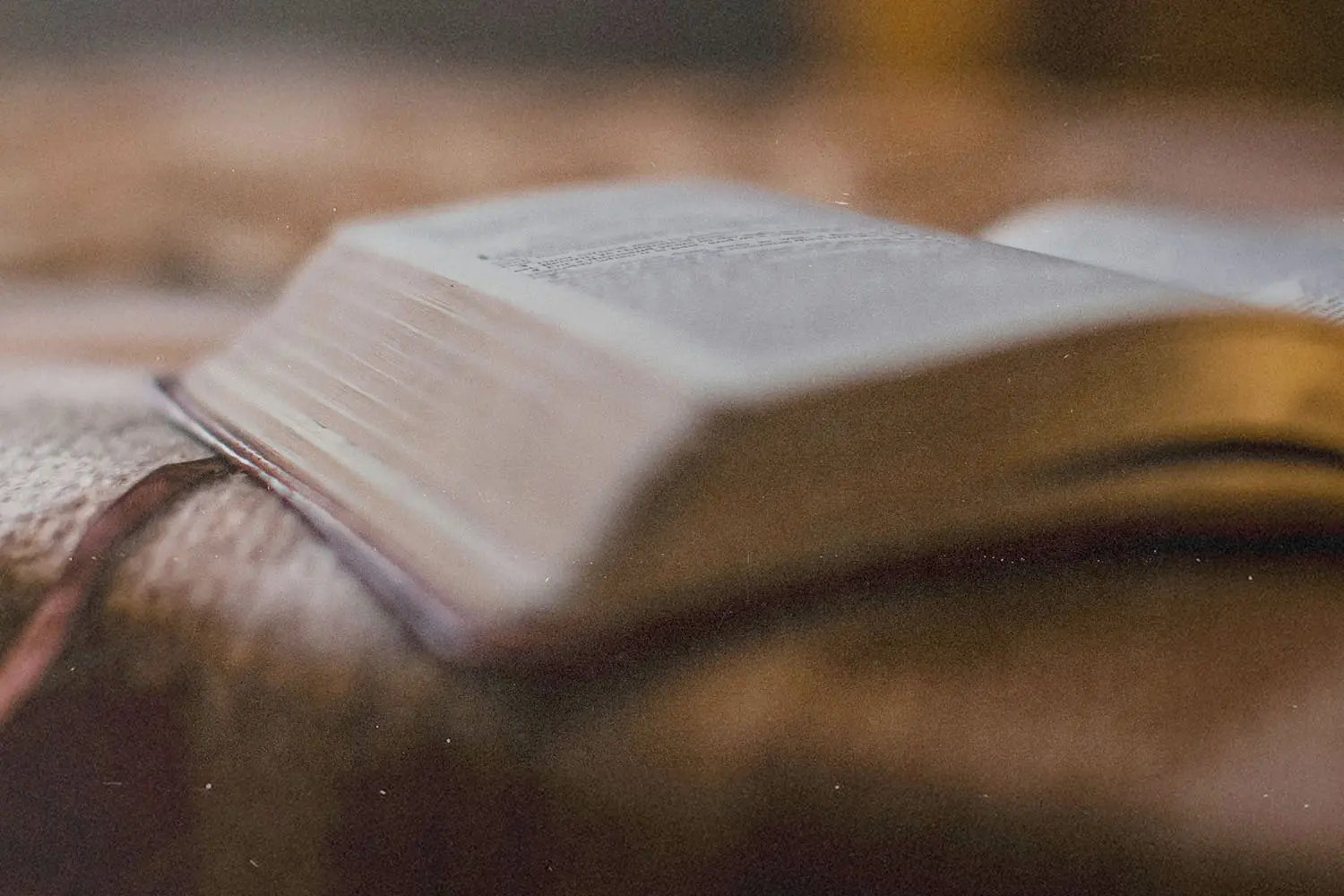 A close-up of an open Bible resting on a soft, textured surface with warm, gentle lighting