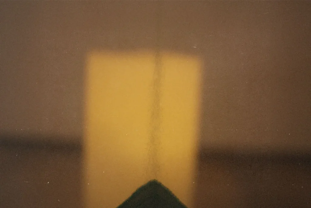 A warm, abstract image showing a vertical line against a glowing yellow rectangular light source in the background