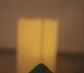 A warm, abstract image showing a vertical line against a glowing yellow rectangular light source in the background