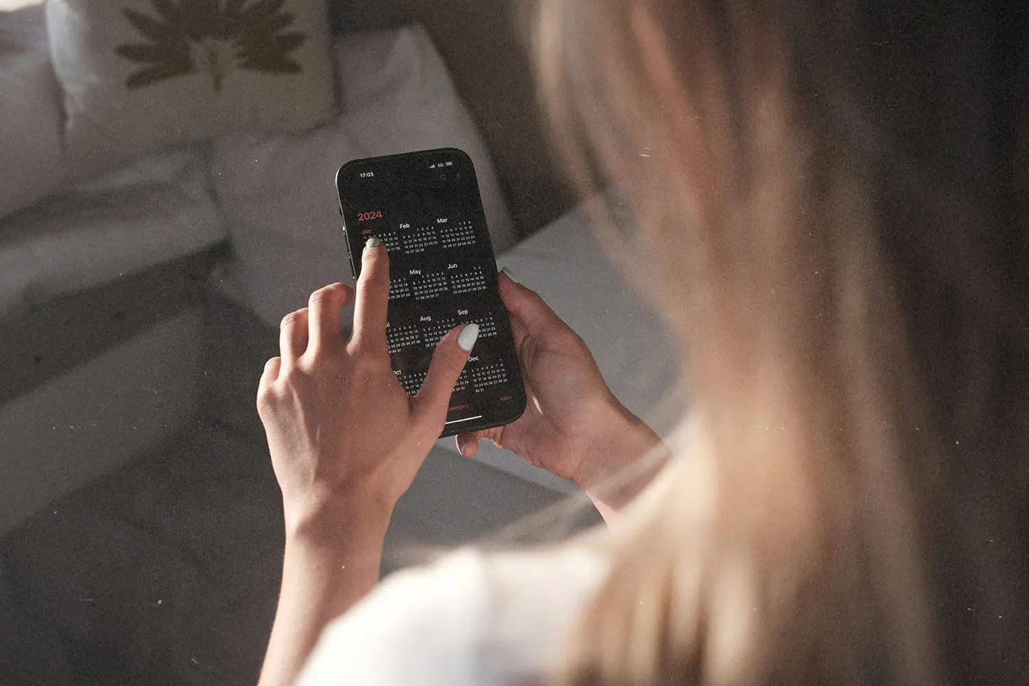 A person uses a smartphone, tapping on a full-year calendar displayed on the screen