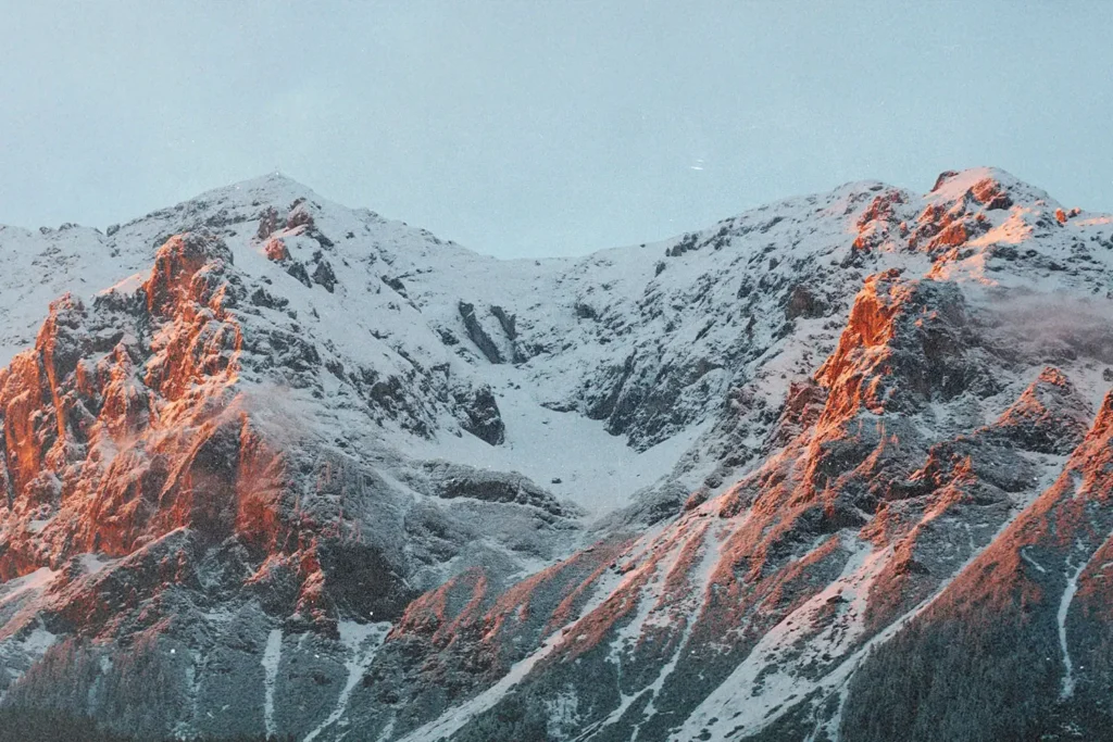 Snow‑covered mountain range illuminated by warm sunrise light along the rocky peaks