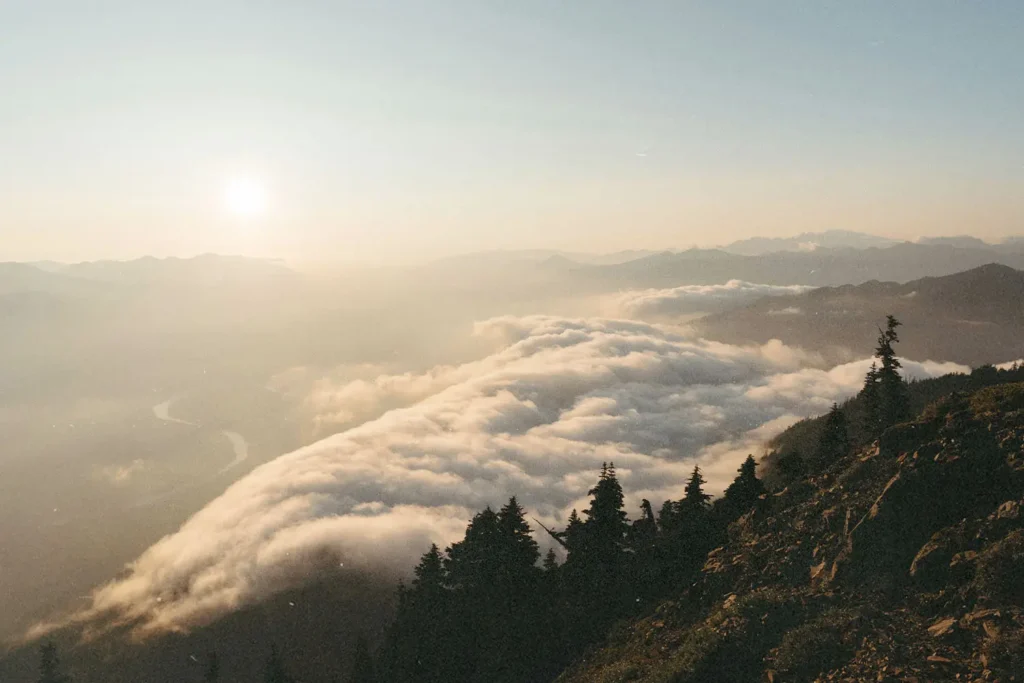 Sunrise casting warm light over mountain ridges and a valley filled with rolling clouds