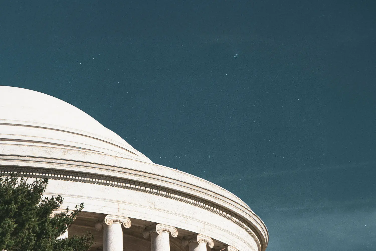 White domed government building with classical columns beneath a clear blue sky