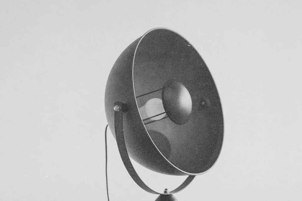 Vintage amplifier horn with a round metal housing against a plain background