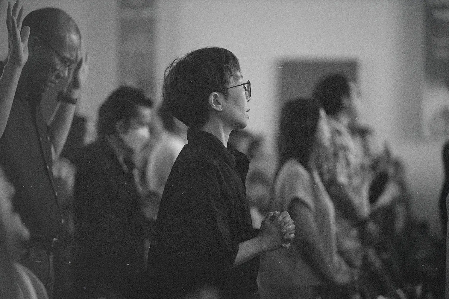 Crowd of people engaged in worship, with hands lifted and bodies turned toward the front