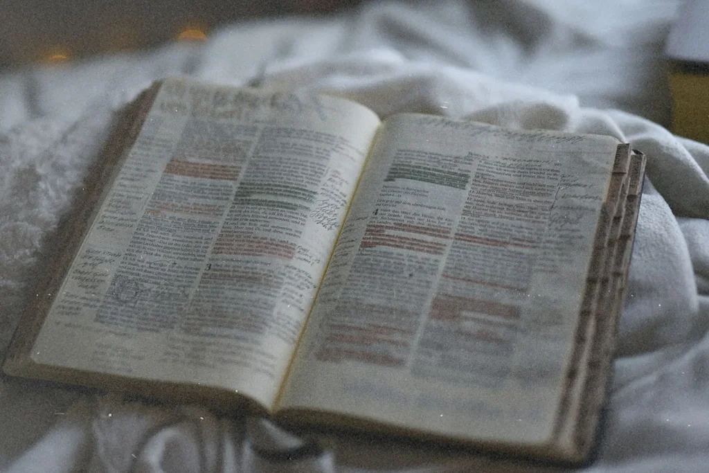 Open Bible with highlighted verses and handwritten notes resting on a soft blanket in gentle, natural light