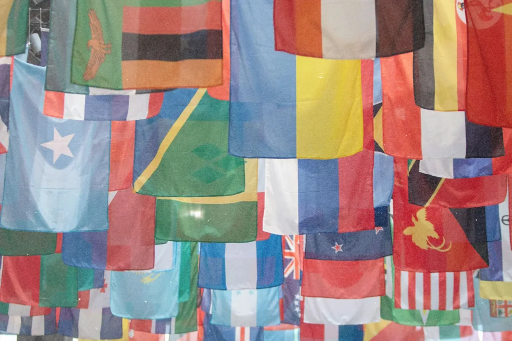 A large collection of colorful international flags hangs overhead in overlapping rows