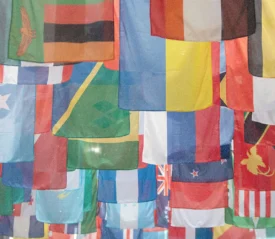 A large collection of colorful international flags hangs overhead in overlapping rows