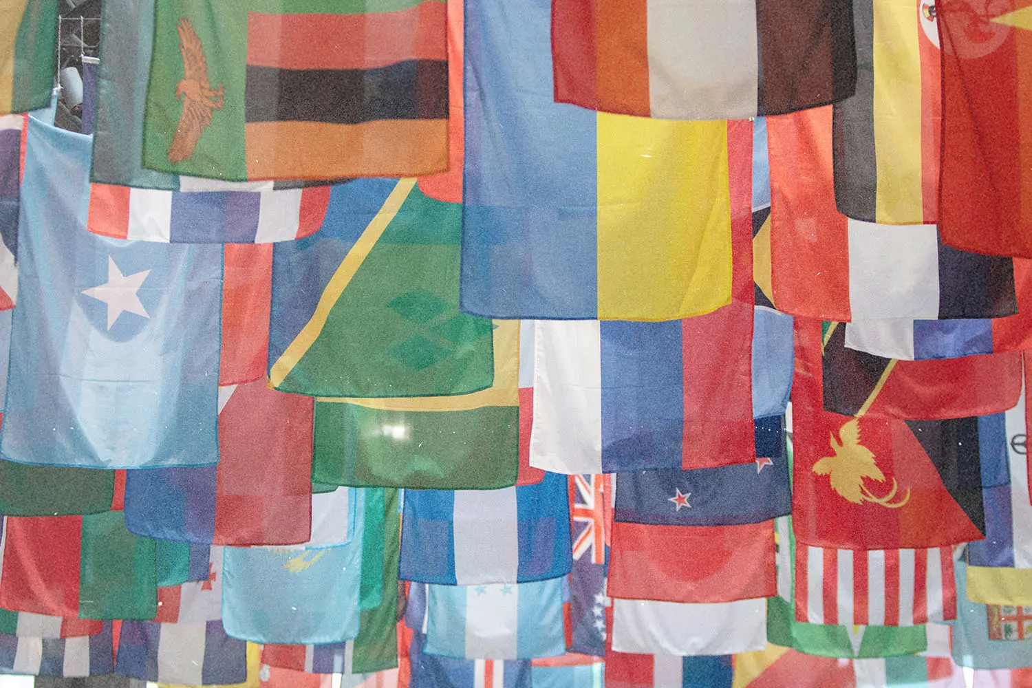 A large collection of colorful international flags hangs overhead in overlapping rows